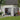 Grey metal storage shed with open double doors, diagonal braces, and tool shelving