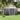 Gray metal apex roof garden storage shed with double doors, standing on a lawn.