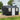 Metal outdoor storage shed with apex roof, front door, and side windows; black and white