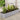 Silver oval raised garden bed with soil and flowering plants, on outdoor patio