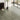 Wood-effect vinyl floor tiles in herringbone pattern, light gray-green tones, peel-and-stick