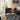 Freestanding electric fireplace heater in front of window with orange flame glow
