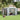 Gray metal apex roof garden storage shed with double doors open, showing tools inside.