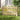 Wooden fence gate with vertical pickets and dark hinge posts, light wood