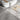 Gray wood-effect PVC plank flooring tiles with peel-and-stick backing near shoes