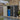 Metal storage shed with open left door, lock latch on front frame, includes blue bin
