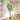 Artificial green faux tree in black pot with upright trunk and layered leafy branches