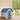 Blue plastic dog house by a wall with arched entrance and clear door opening