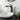 Black single-handle basin mixer tap with curved spout above round white sink.