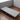 Folding bed with light gray mattress panels and black metal legs, on caster wheels