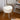 White round plush footstool with padded seat and white metal legs