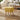 Yellow linen-upholstered footstool with tufted top and light wooden legs, angled