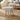 Beige upholstered linen footstool with square top and light wooden tapered legs