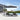 Cantilever square garden parasol with dark canopy over patio table and chairs