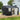 Metal storage shed with open door and front windows; black body with light trim
