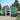 Green metal garden storage shed with apex roof and sliding door open to interior storage