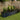 Dark oval raised garden bed planter with ribbed sides, filled with flowers and greenery