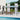 Wall-mounted canopy gazebo with dark metal frame and clear polycarbonate roof panels
