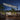 Cantilever garden parasol with grey canopy and solar LED string lights, black pole at night