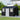 Metal outdoor storage shed with apex roof, windows, vents; black and white exterior