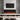 Recessed electric fireplace with dark glass front and orange-red flame over logs