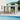 Wall-mounted canopy gazebo with dark frame and clear polycarbonate roof over chairs