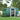 Green metal garden storage shed with apex roof and sliding door open, showing interior frame